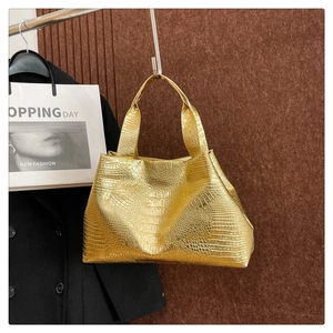 Detail of gold faux leather tote bag featuring realistic crocodile pattern texture