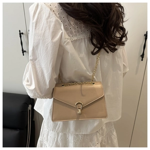Detailed close-up of beige crocodile pattern leather bag with golden U-shaped buckle