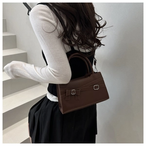 Fashionable dark brown crossbody bag with bow detail shown on a model by stairs