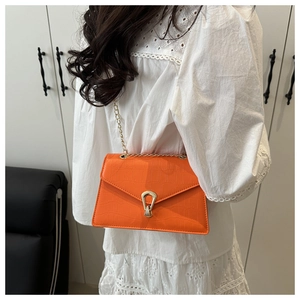 Detail of orange crocodile pattern crossbody bag with a golden turn-lock closure