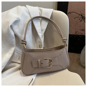 Detail of beige faux leather baguette bag featuring a gold buckle and knotted shoulder strap