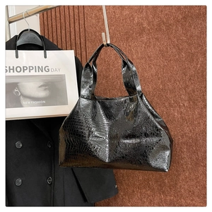 Close-up of black crocodile embossed tote bag texture with glossy finish and dual handles