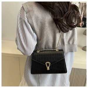 Detail of black crocodile texture shoulder bag with gold chain strap and U-shaped buckle