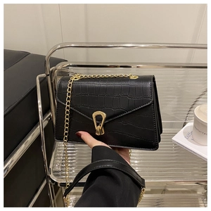 Detail of black crocodile texture bag with gold chain strap and metal horseshoe buckle