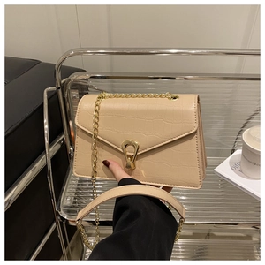 Close-up of beige crocodile pattern leather handbag with gold U-shaped buckle and chain