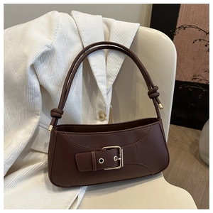 Detail of dark brown leather underarm bag with gold buckle and knotted strap on white blazer