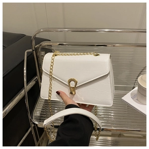 Detail of white crocodile-embossed leather cross-body bag with golden drop-shaped lock