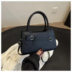 Detail of black faux leather handbag featuring a chic bow and silver metallic buckles