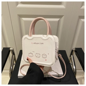 Détail d'un mini sac carré en cuir crème avec poignées roses et imprimés oursons