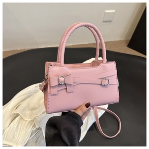 Close-up of pink handbag showing bow detail, buckle straps and smooth PU leather texture
