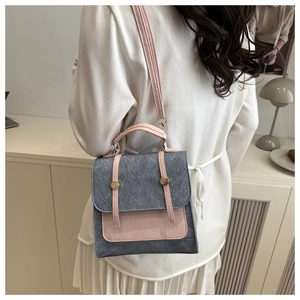 Detail of grey and pink bicolor mini shoulder bag shown on a model in a minimalist setting