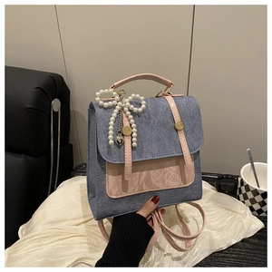 Détail d'un mini sac à dos en denim rose avec nœud perlé et pendentif en forme de cœur