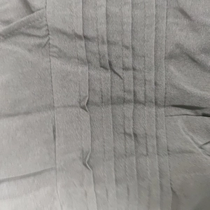 Macro detail of grey pleated fabric texture showing fine vertical fold patterns on jumpsuit