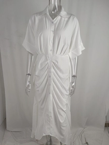 Détail des plis à la taille et fermeture boutonnée sur robe chemise blanche