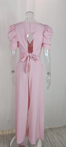 Detailed back view of pink v-neck jumpsuit featuring open back and oversized bow tie detail