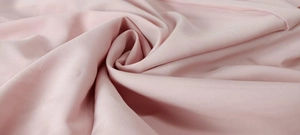 Detail of soft pale pink satin fabric with smooth texture and elegant drapes