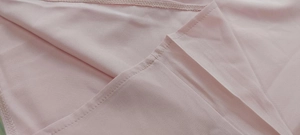 Macro detail of soft pink chiffon fabric texture and high-quality stitching on the jumpsuit