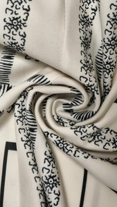Macro shot of beige fabric with black abstract tribal print showing textile texture and drape