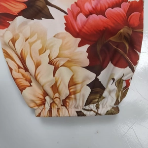 Dettaglio dei polsini elastici di un abito floreale con scollo a V e stampe di peonie