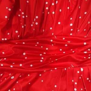 Détail du tissu rouge à pois blancs avec plis élégants et texture de robe raffinée