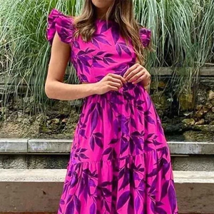 Dettaglio dell'abito lungo fucsia a fiori con ritagli sui fianchi e maniche a volant