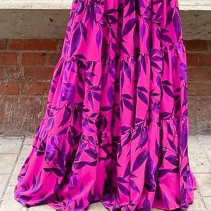 Dettaglio di un vestito lungo a fiori fucsia con motivi a foglia viola all'aperto