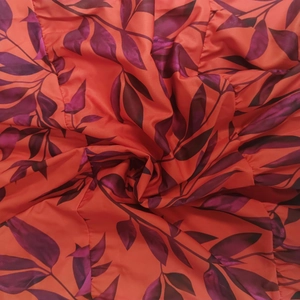 Dettaglio del tessuto rosso con stampa di foglie viola e texture con increspature