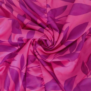Dettaglio del tessuto fucsia setoso con stampe di foglie viola e morbida vestibilità