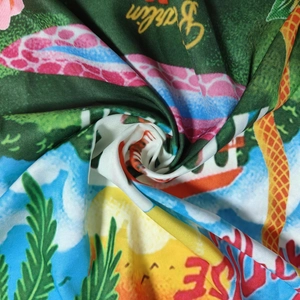 Detailed view of tropical print satin fabric with palm leaves and Berlin lettering
