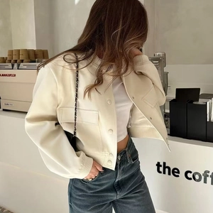 Detalle de una elegante chaqueta color crema con bolsillos en entorno de café