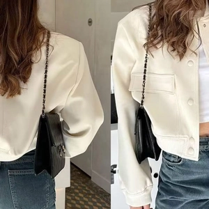 Detalle de chaqueta elegante blanco roto con cuello alto y bolso de cadena acolchado