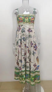 Detailed pattern of floral and bird prints on a white maxi dress with green borders