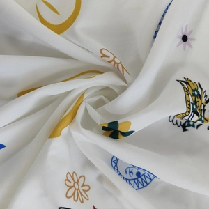 Gros plan du tissu blanc avec des motifs colorés de soleil, lune et fleurs imprimés