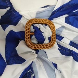 Détail de la robe élégante à col en V avec imprimé géométrique bleu et boucle décorative