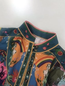 Dettaglio dell'elegante collo alto e bottoni vintage su un abito a stampa colorata
