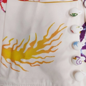 Detail view of multicolored fabric-covered buttons and orange floral print on a shirt