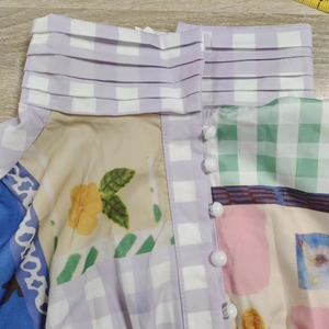 Détail du col montant à volants et boutons blancs sur une robe imprimée patchwork