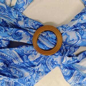 Dettaglio del tessuto paisley blu e bianco con una fibbia in resina marrone sul vestito