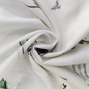 Dettaglio di tessuto satinato bianco con stampa floreale verde e elegante testo corsivo