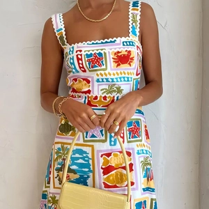 Close-up of white summer dress with tropical ocean prints and white ricrac strap details