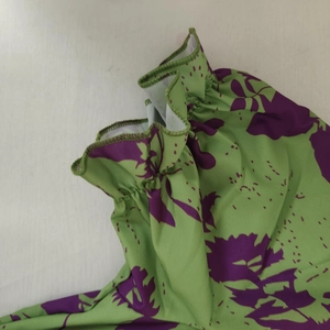 Detail of smocked elastic cuff and purple floral print on green v-neck summer dress