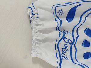 Detailed view of elastic smocked cuff and blue ocean print with Soleil text on dress