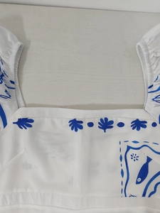 Detailed view of square neckline and blue leaf print on a white puff sleeve top