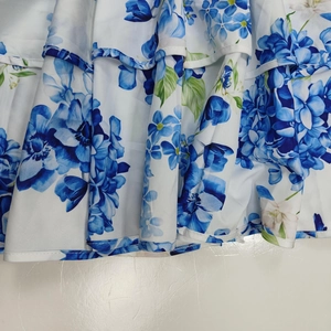 Close-up of tiered ruffle hem with blue floral print on white chiffon dress fabric