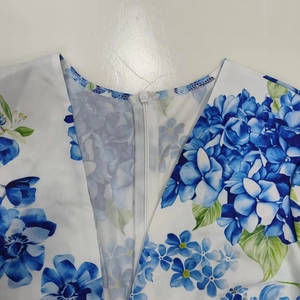 Detail of elegant V-neckline with white nylon zipper on floral print dress fabric