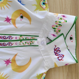 Detail of printed lapel and translucent buttons on a white casual shirt with pop art icons