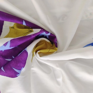 Detailed view of floral leaf print on white satin fabric with soft texture and drape