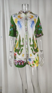 Detail of printed shirt set featuring green crocodile and moon motifs on white fabric