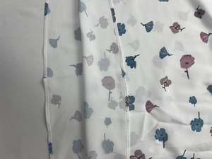 Detail of white floral chiffon fabric showing blue flower prints and hem stitching