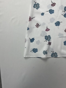 Detailed close-up of blue and purple floral print on white elegant dress fabric